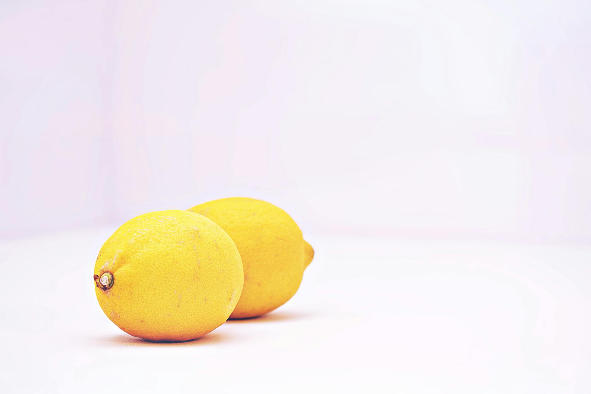 Two women laughing together indoors with fresh lemons, expressing joy and connection