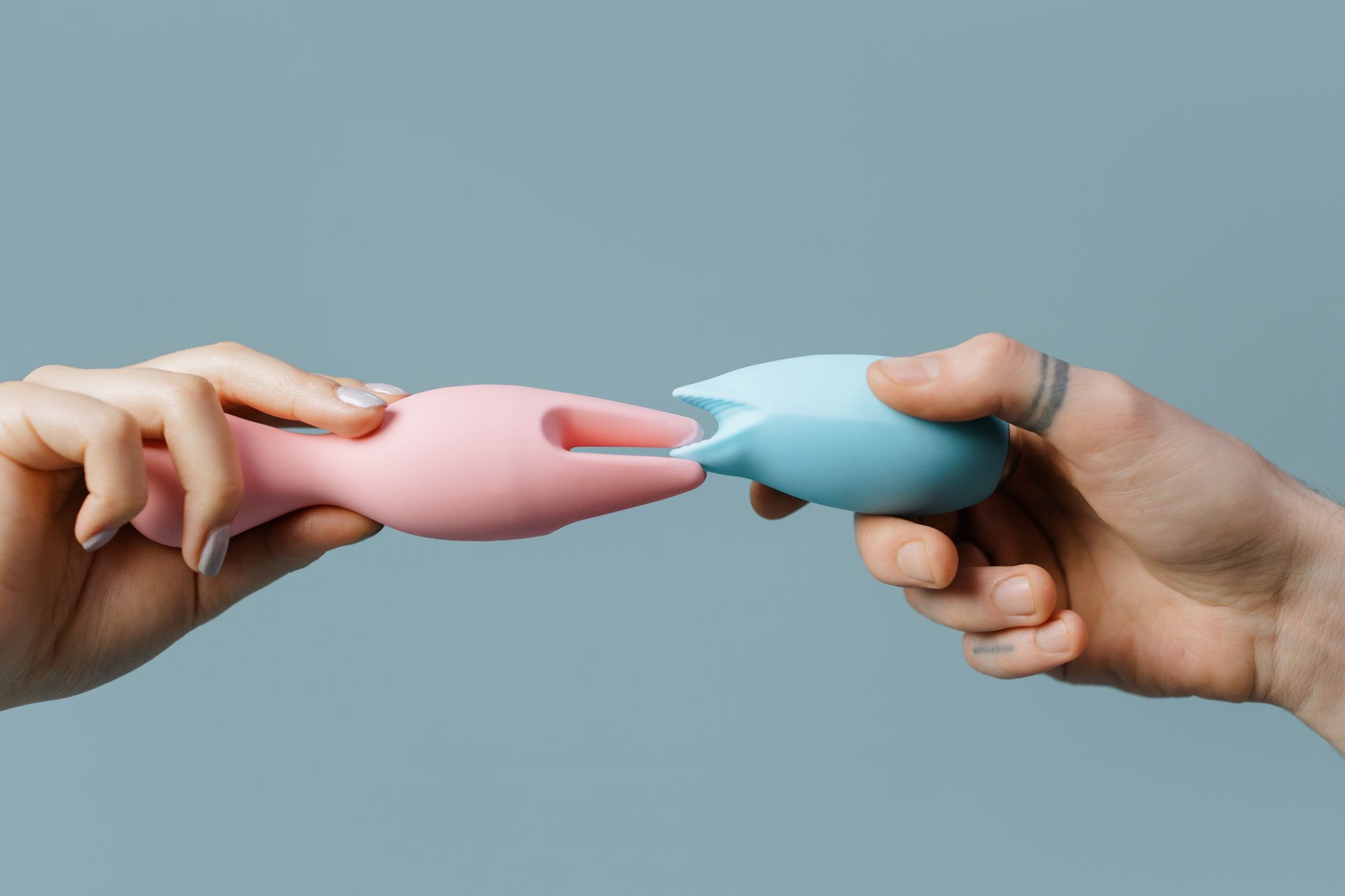 Manos sosteniendo juguetes sexuales de colores pastel, mostrando opciones modernas para la intimidad