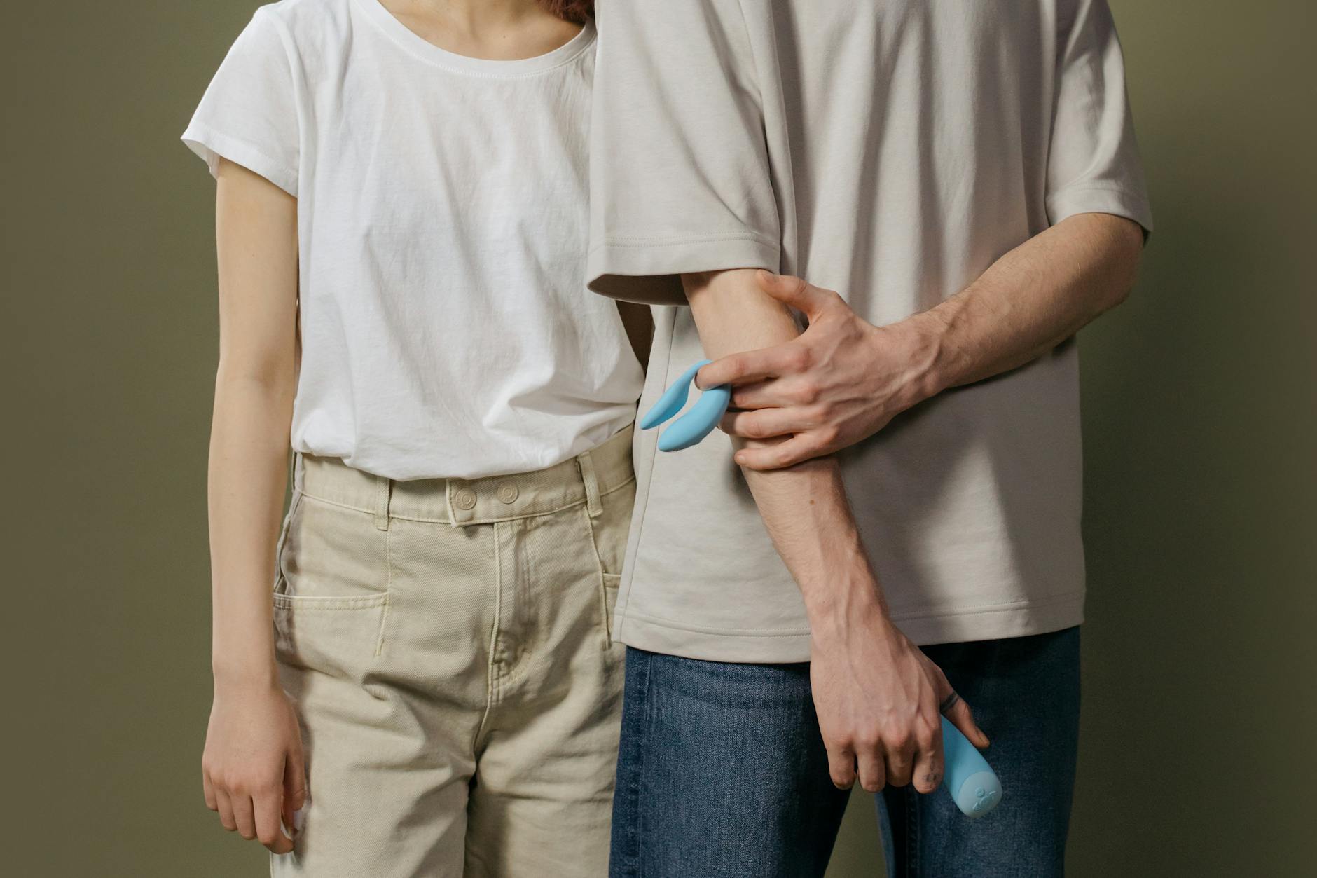 A hand holding a modern clitoral suction vibrator against a minimalist backdrop
